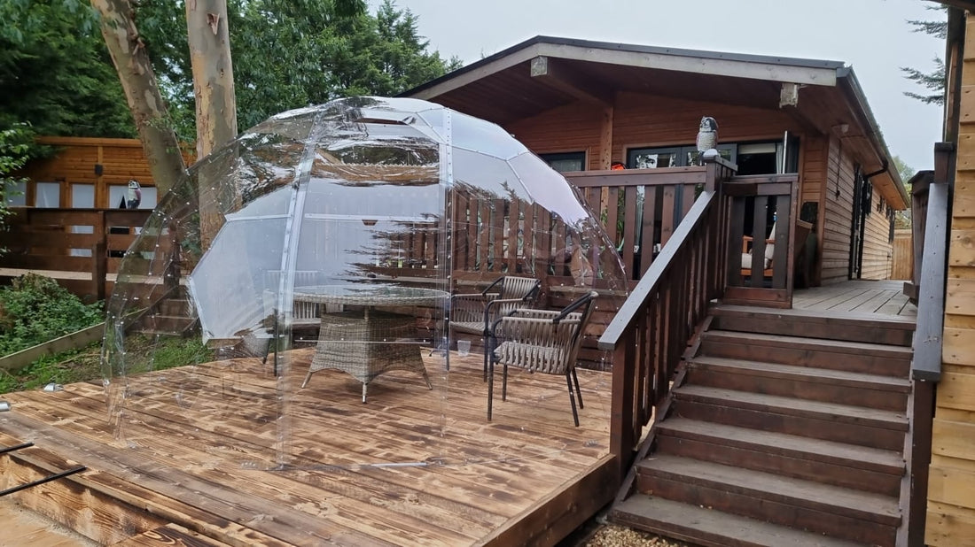 A GeoDomeX dome on decking beside a timber cabin